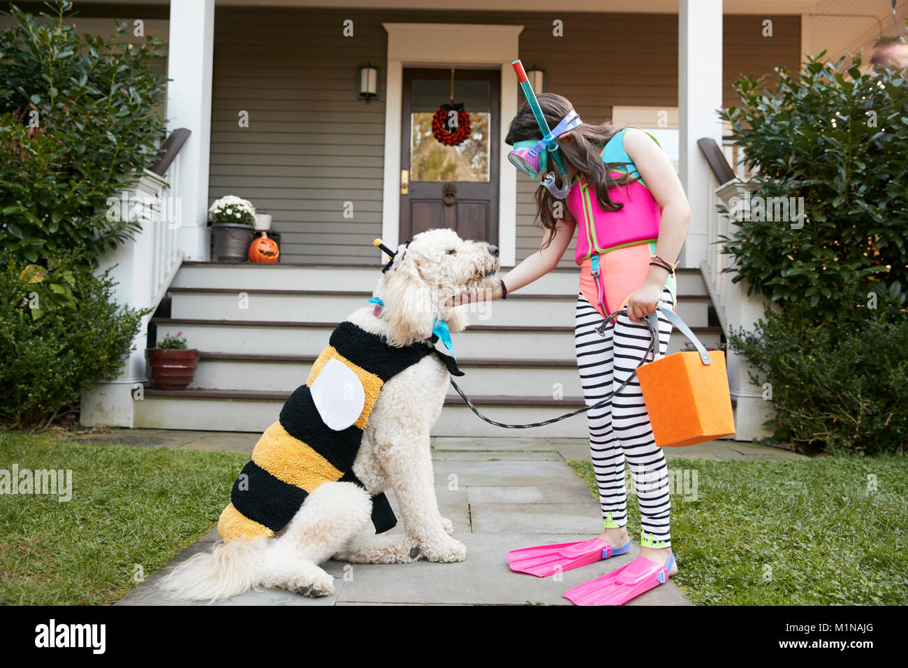 Girl With Dog Wearing Halloween Costumes For Trick Or Treating Stock Photo