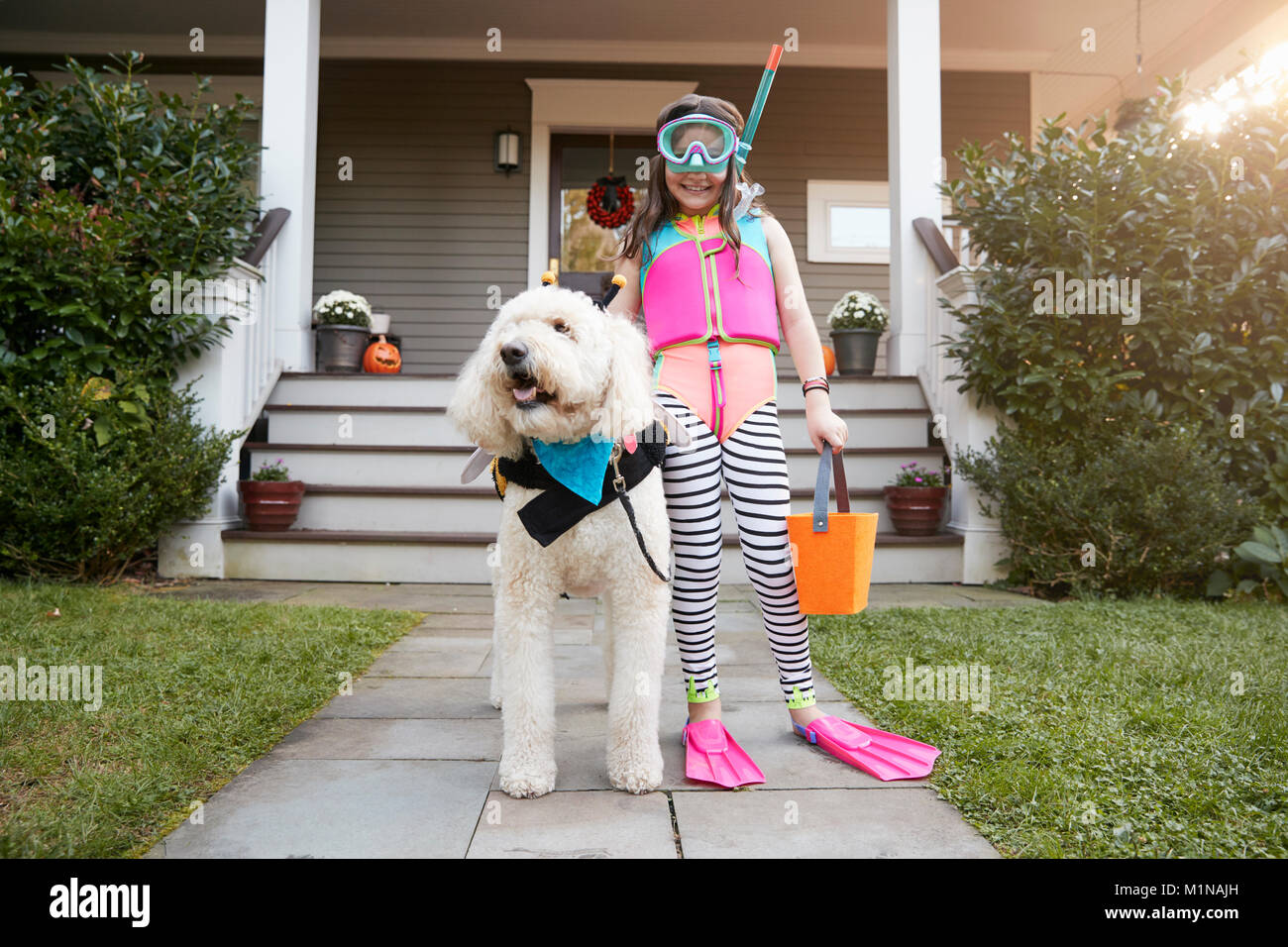 Girl With Dog Wearing Halloween Costumes For Trick Or Treating Stock Photo