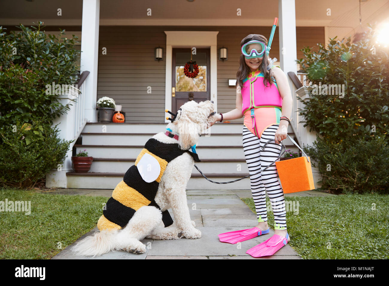 Girl With Dog Wearing Halloween Costumes For Trick Or Treating Stock Photo
