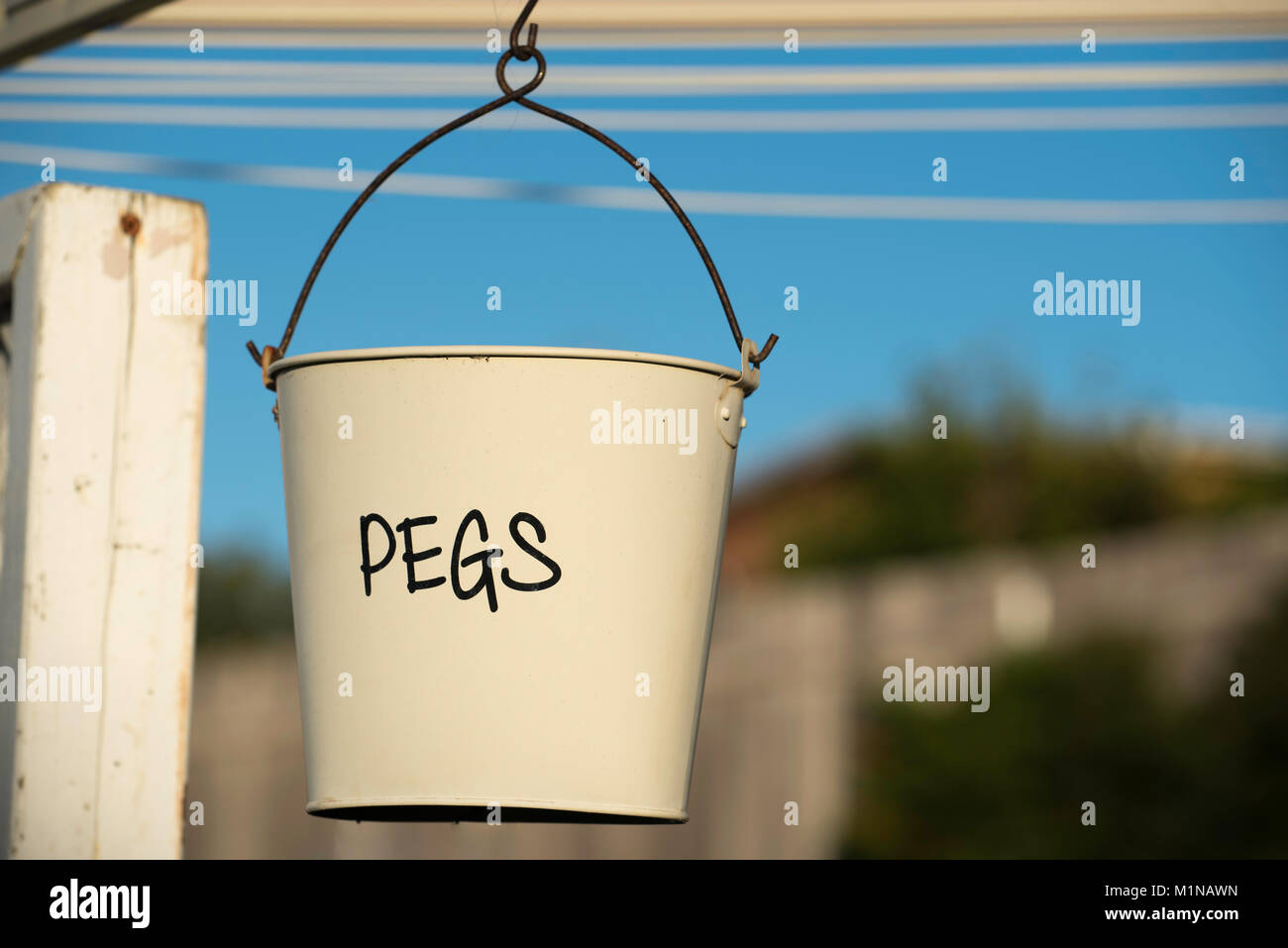 A clothes pegs or pins bucket hangs from a clothes line in an
