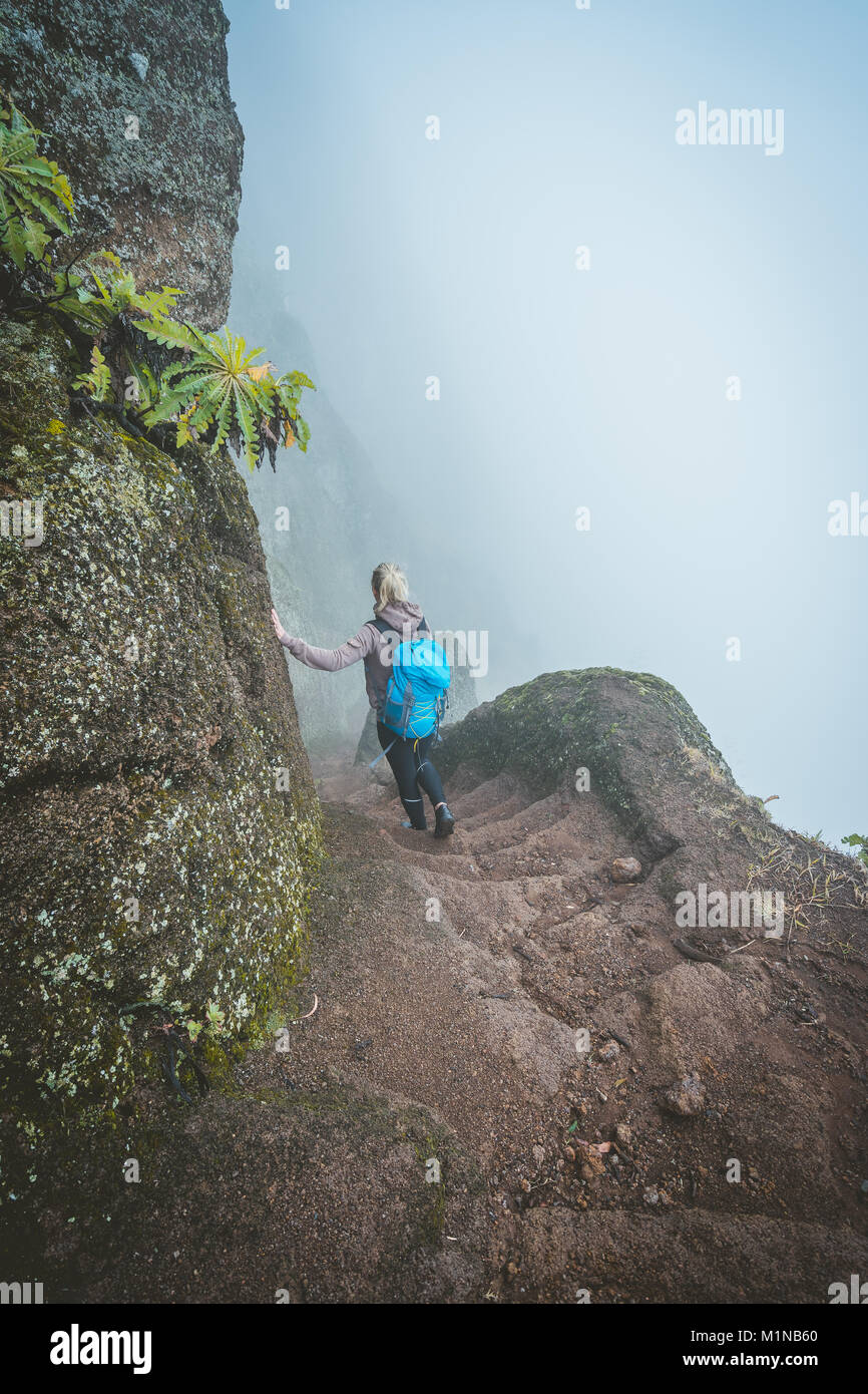 Female hiker with blue backpack staying on the stony cobbled