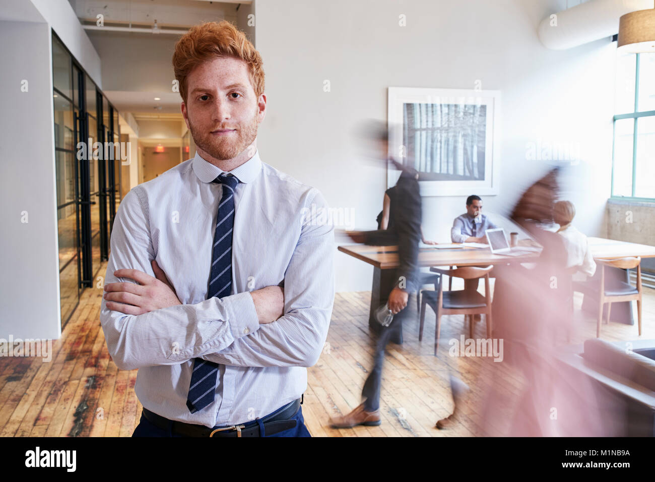 Portrait of young red haired man in a busy modern workplace Stock Photo