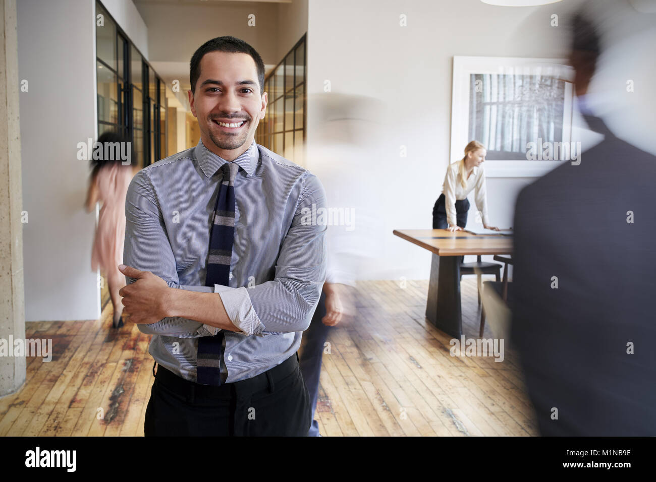 Portrait of young Hispanic man in a busy modern workplace Stock Photo