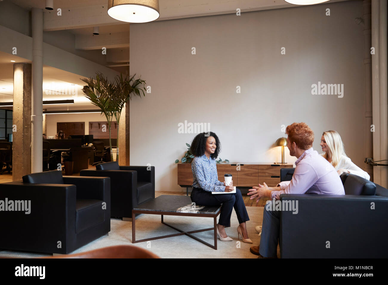 Three colleagues at a casual work meeting in a lounge area Stock Photo