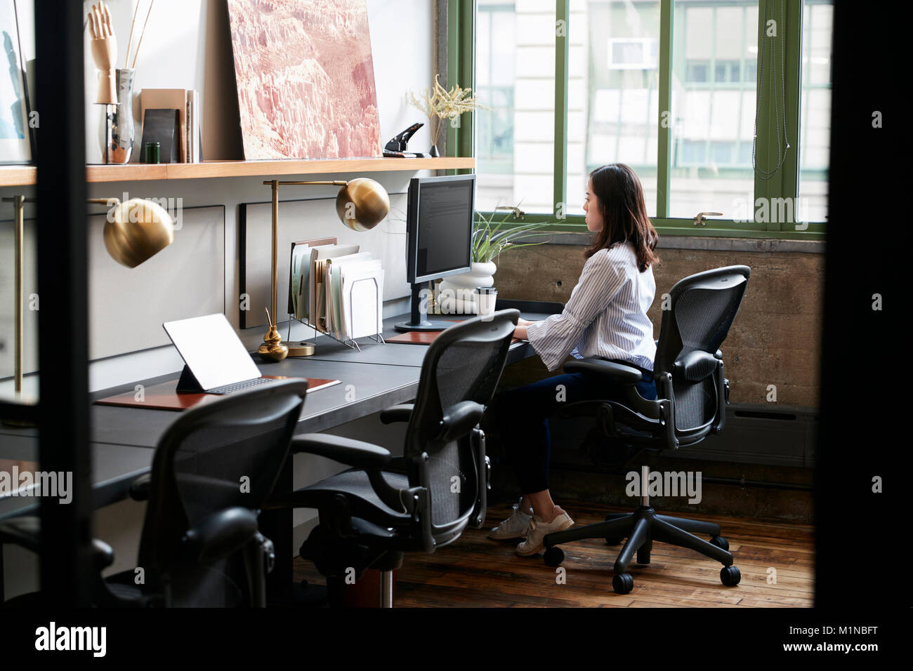 Young woman working alone in a compact office Stock Photo