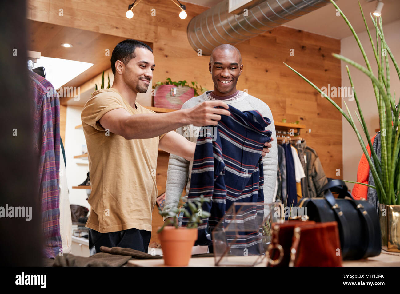 Two young men holding up clothes to look at in clothes shop Stock Photo