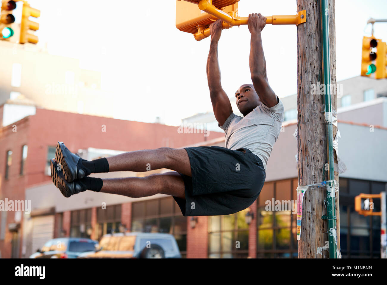 Young black man doing pull ups from crossing light in street Stock Photo