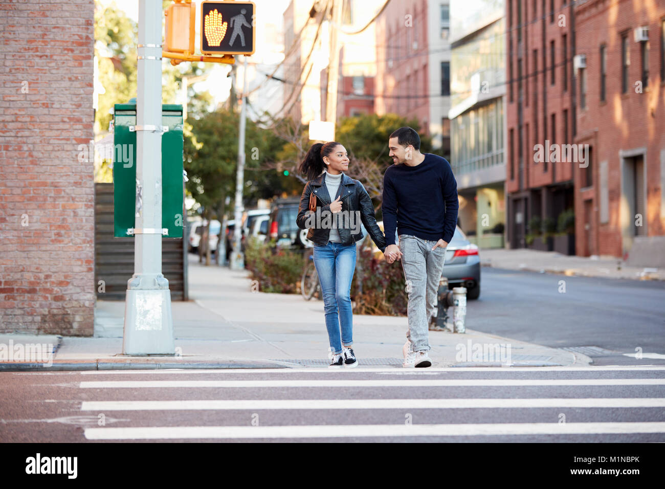 Young Hispanic couple walk hand in hand in Brooklyn street Stock Photo