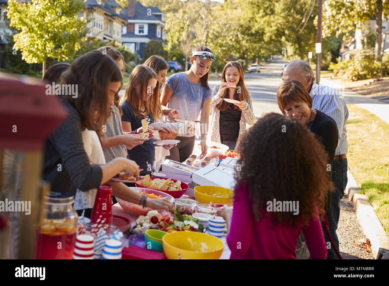 Neighbours standing around a table at a block party Stock Photo