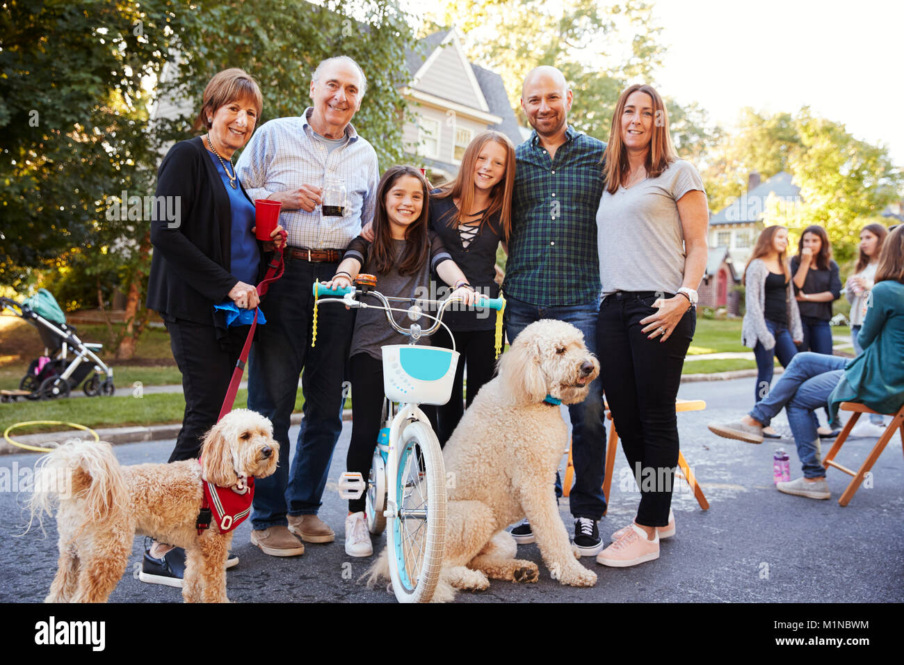 Neighbours with pet dogs smiling to camera at a block party Stock Photo