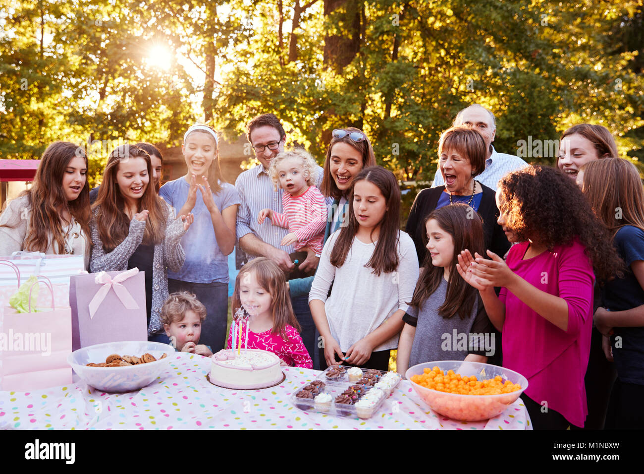 Young girl blowing out candles at her birthday garden party Stock Photo ...
