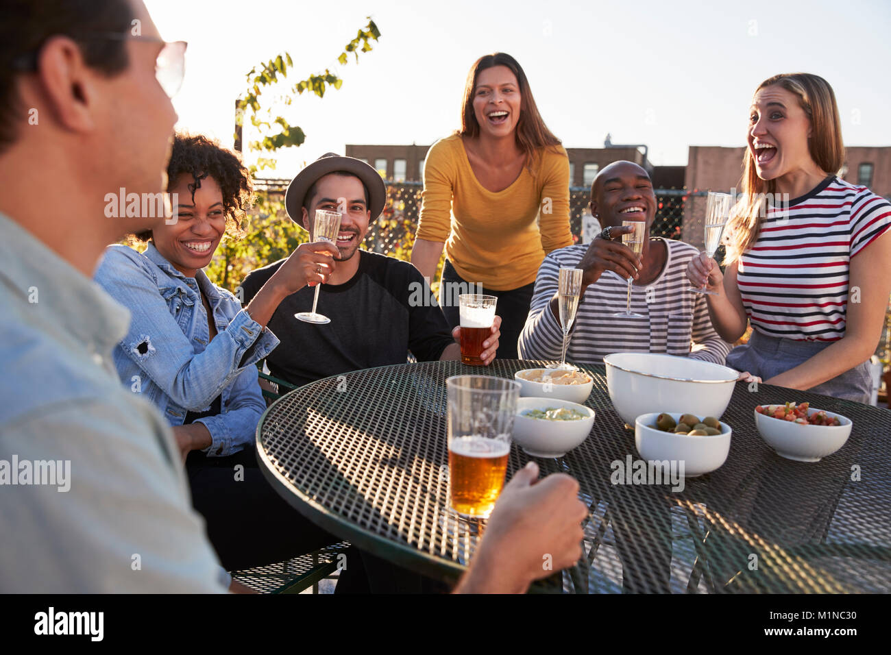 Friends talking and drinking on a New York rooftop, close up Stock Photo