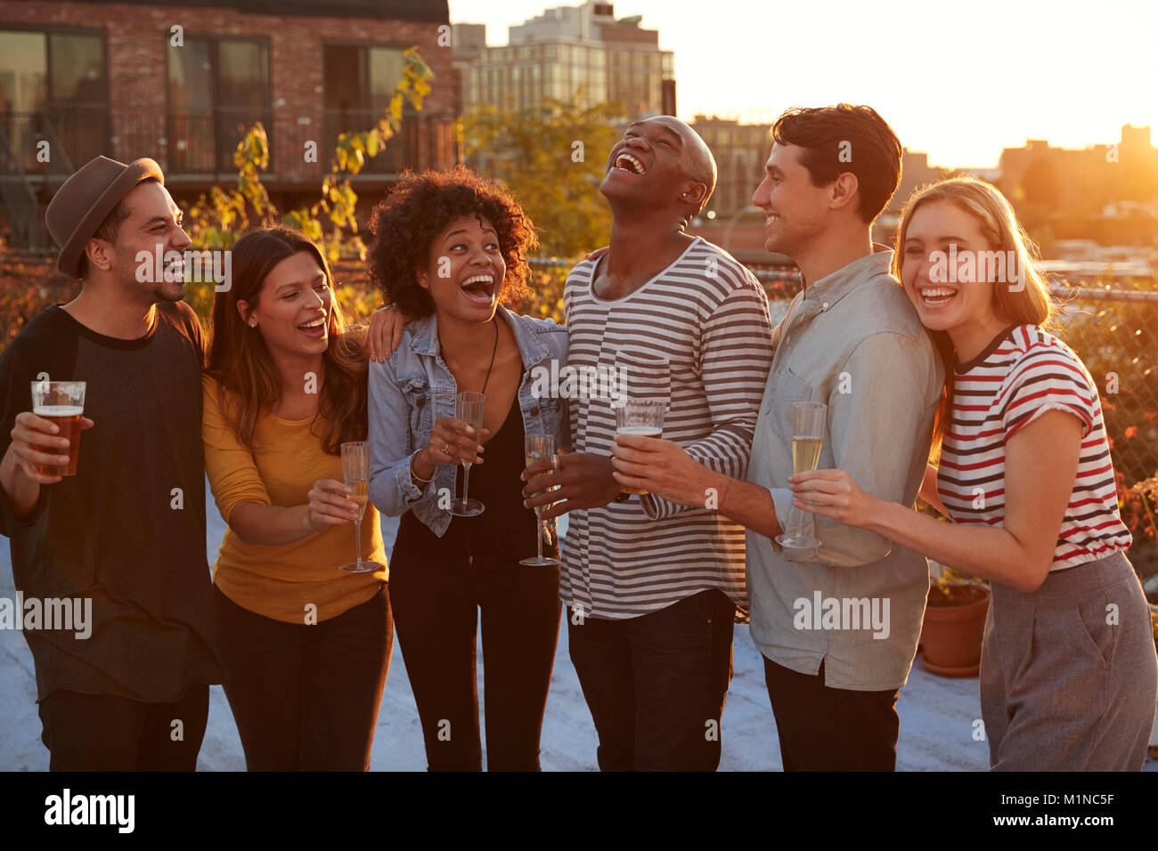 Friends drinking and laughing at a rooftop party in Brooklyn Stock Photo