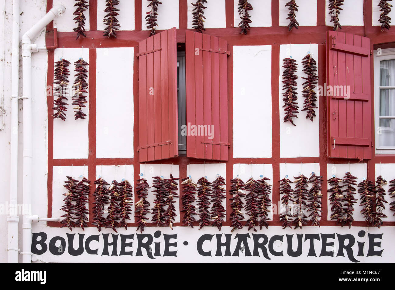 Espelette pepper strings hanging against the facade of a butchery in Espelette, France Stock Photo