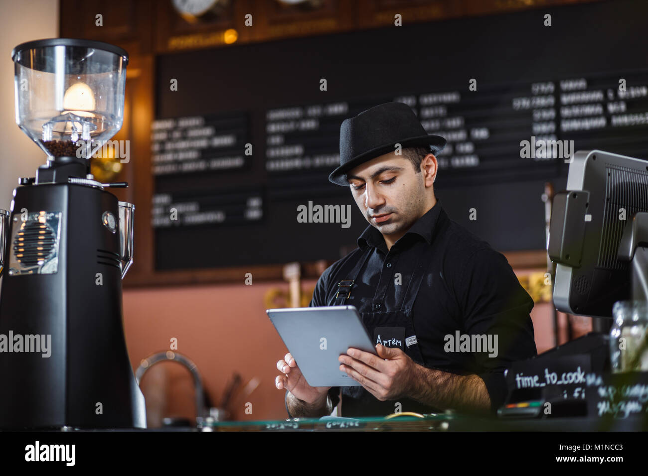 Portrait of barista holding digital tablet at counter in coffee shop. Stock Photo