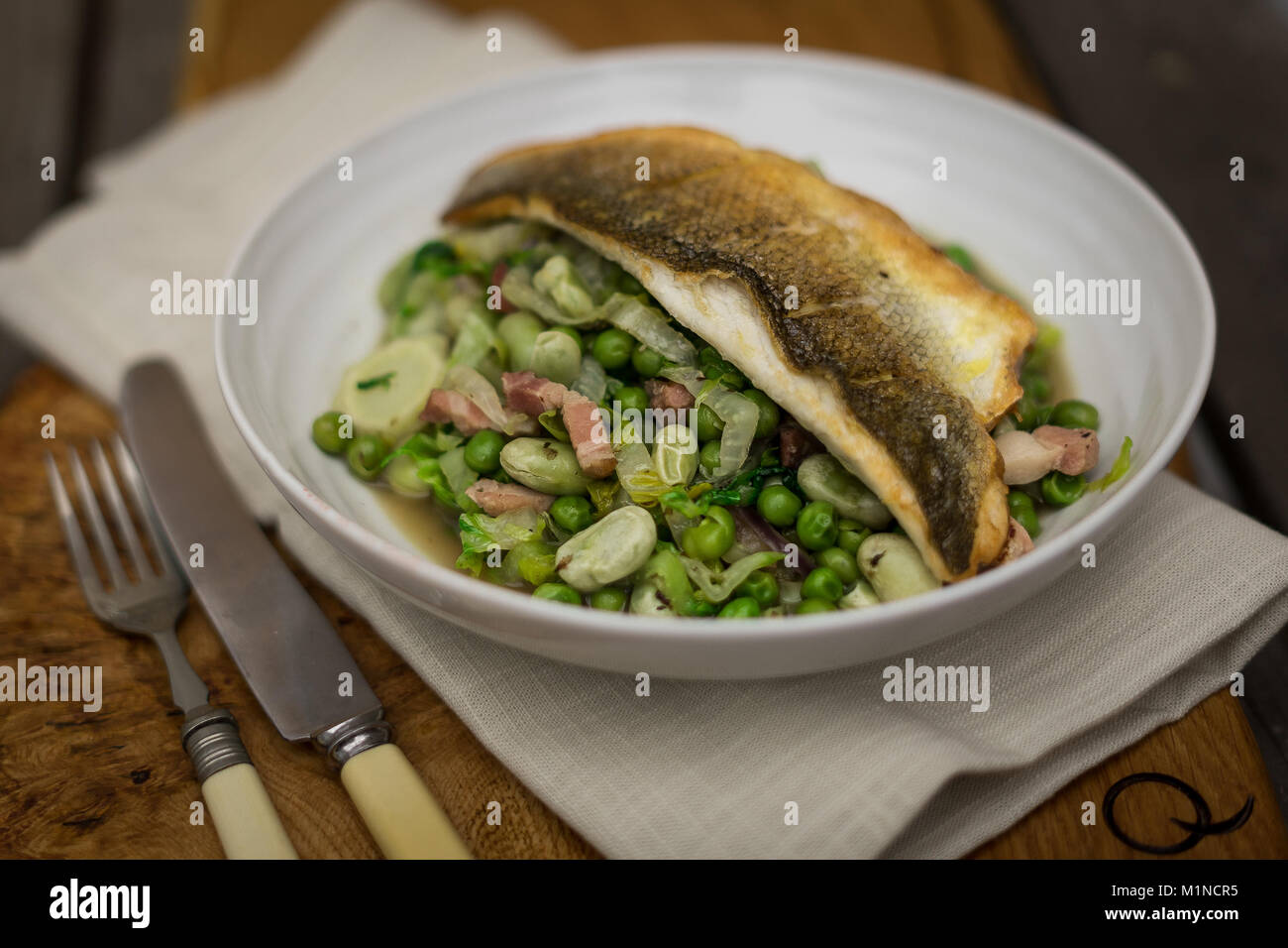 Pan Fried Sea Bass with Petit Pois a la Francais Stock Photo