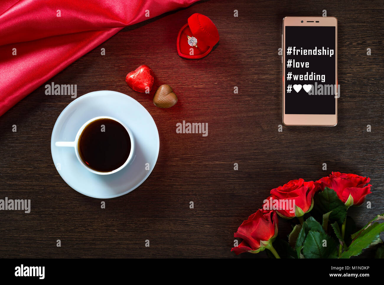 Romantic background with wedding ring, rose flowers, smartphone, cup of