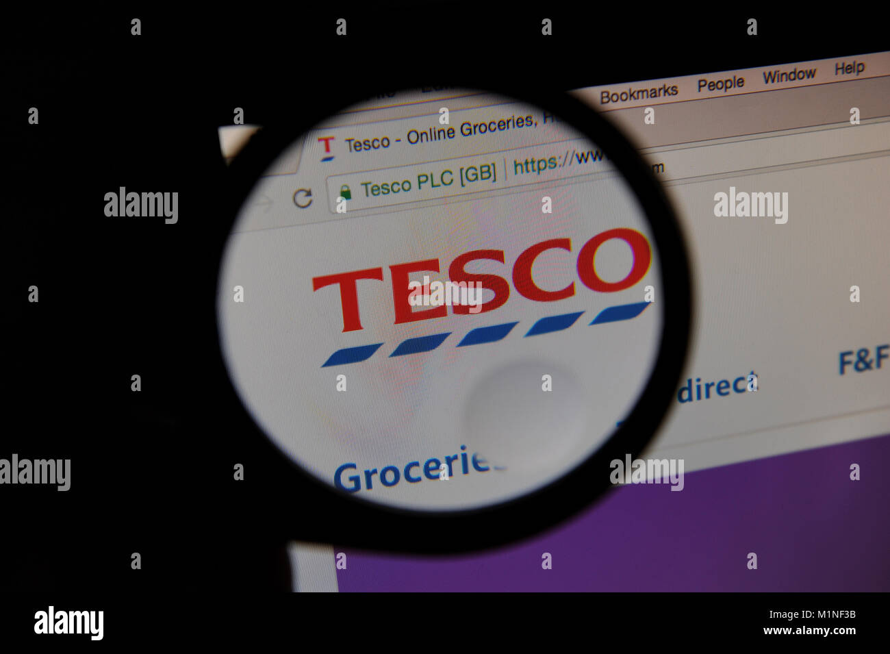 Supermarket Tesco's website is seen through a magnifying glass Stock