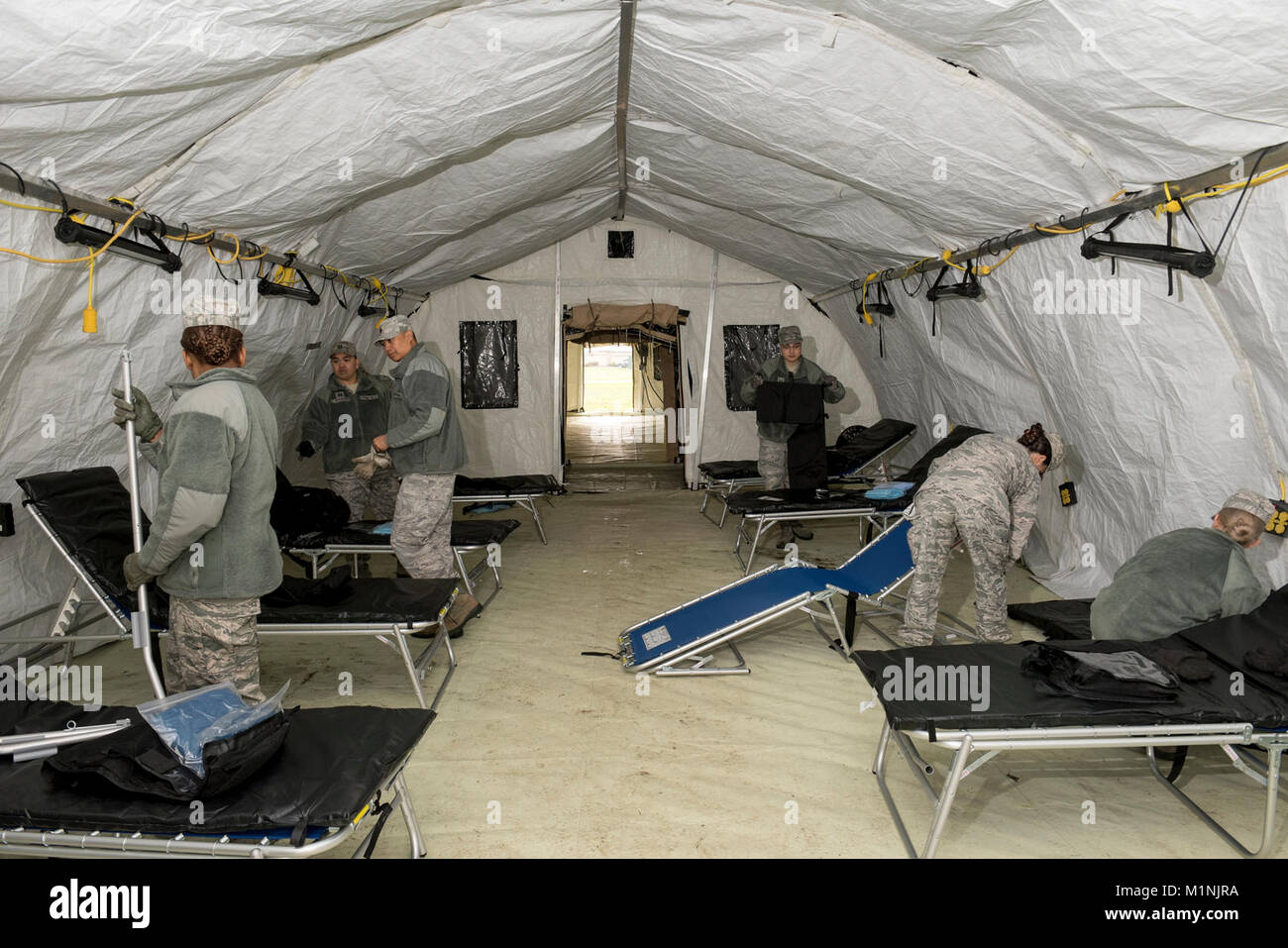 Airmen assigned to the 60th Medical Group set up cots in an EnRoute Patient Staging System at