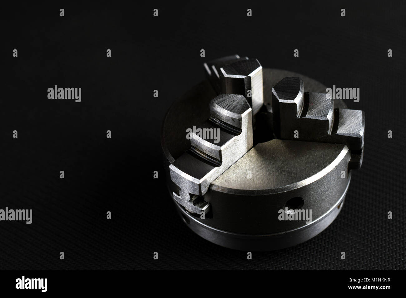 3 jaw chuck for metal lathe on black background. Horizontal industrial background image with space for text. Stock Photo