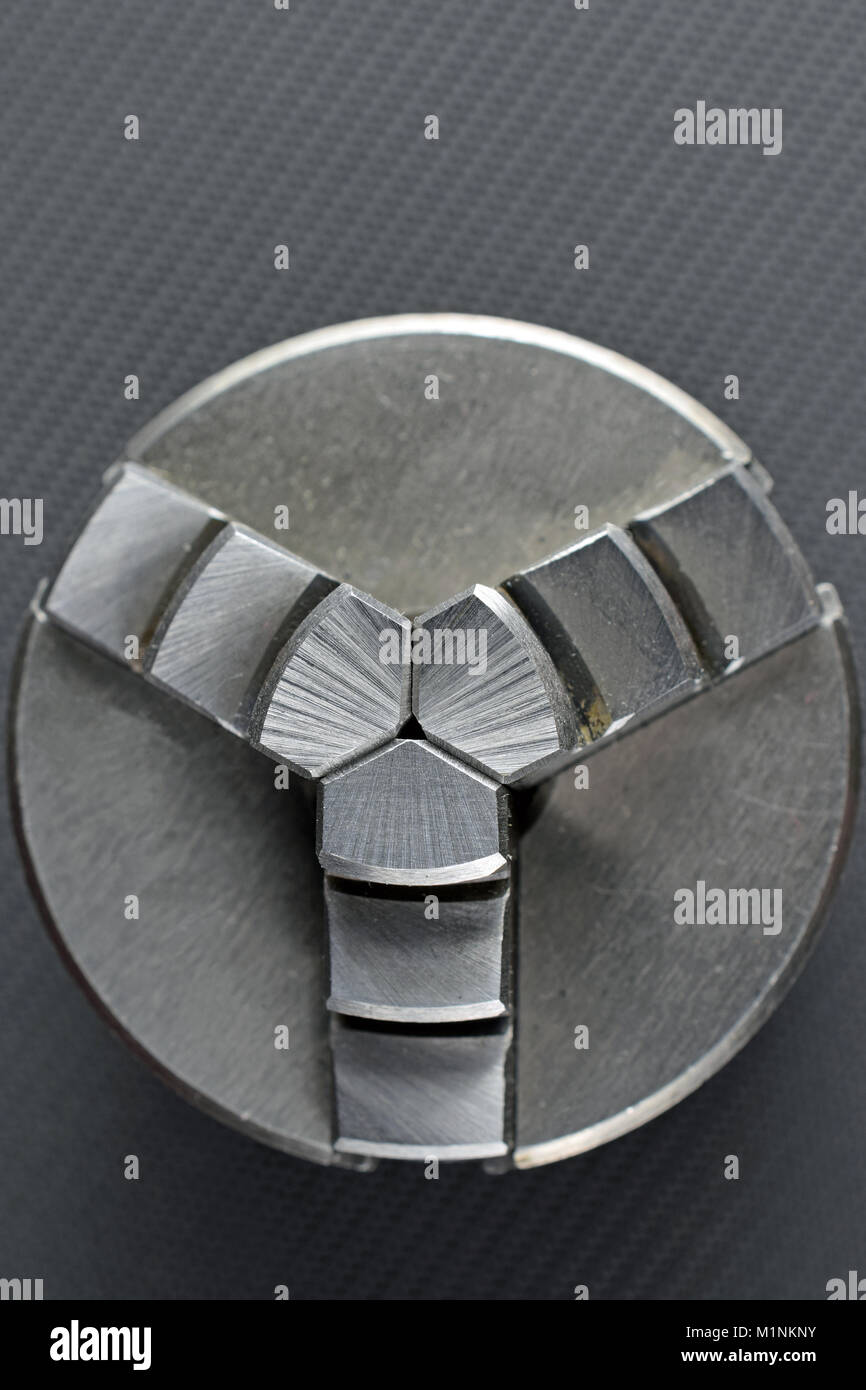 3-jaw chuck for metal lathe on dark background. Vertical top view image with roomfor text. Stock Photo