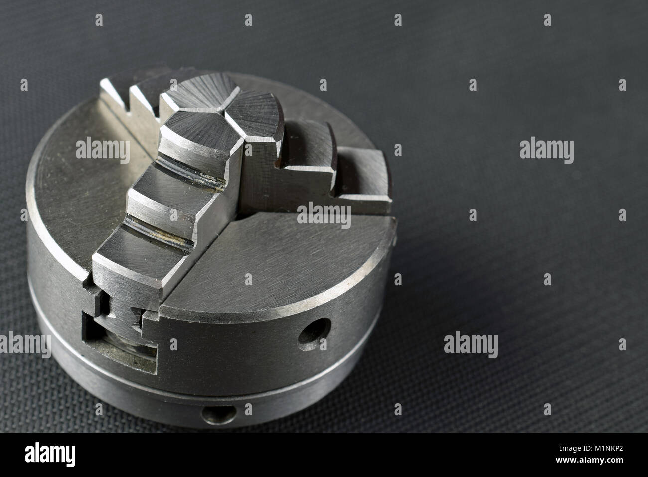 Chuck for metal lathe on dark background. Space for text. Stock Photo