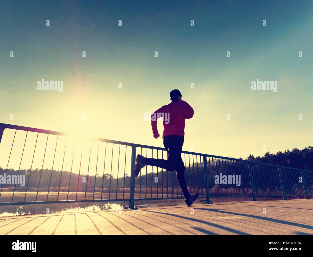 Rear view to runner in blue t-shirt and black leggings running on ...
