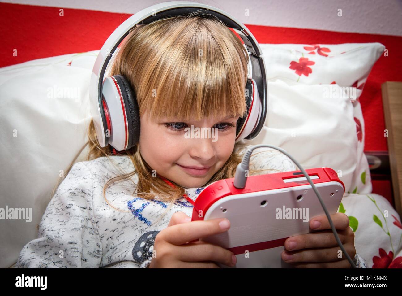 6 year old girl with headphone on plays with a Nintendo DS on a bed,  Kernen, Germany, Nov. 5, 2017. | usage worldwide Stock Photo - Alamy
