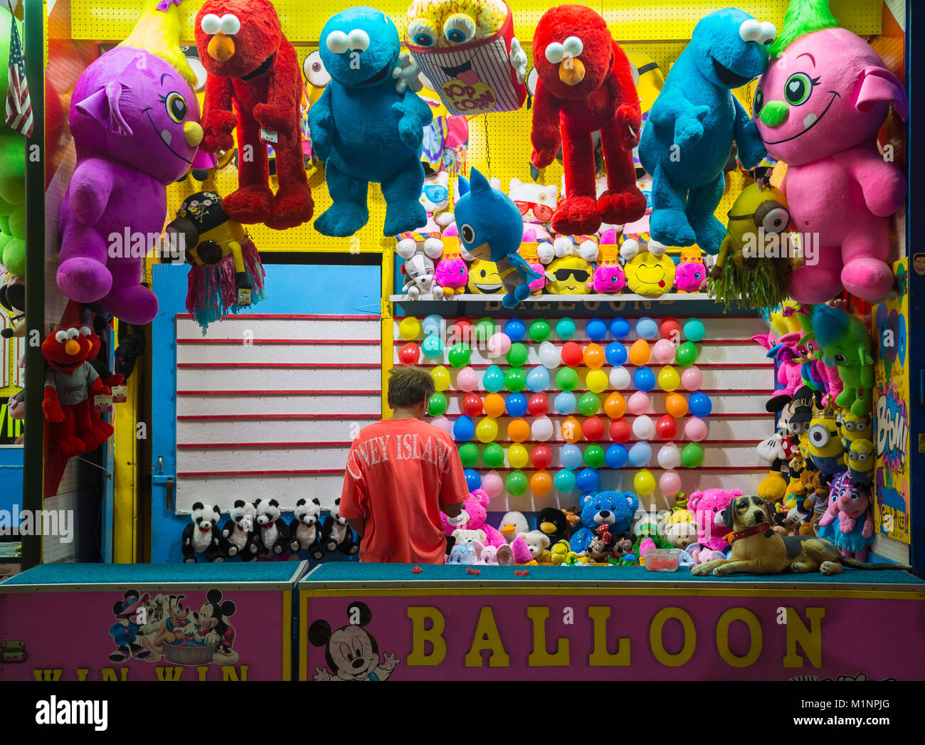 NEW YORK CITY - AUGUST 15, 2017: A worker stands in a balloon-popping booth at the Coney Island boardwalk amusement park. Stock Photo