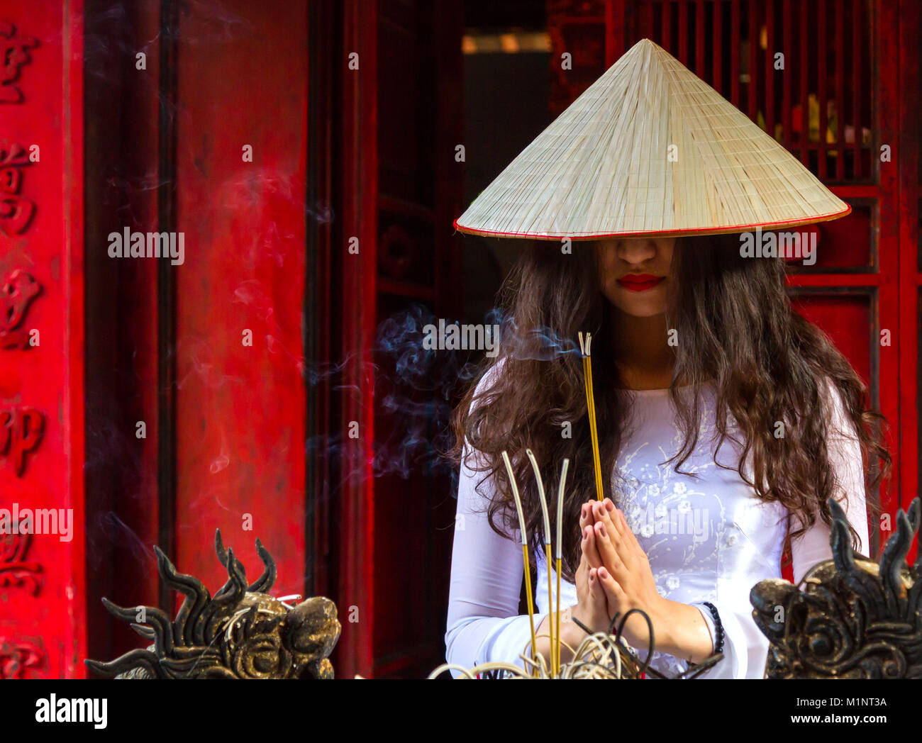 Young Vietnamese woman in Temple of Literature, Hanoi, Vietnam. She is wearing the traditional Ao Dai dress. Stock Photo