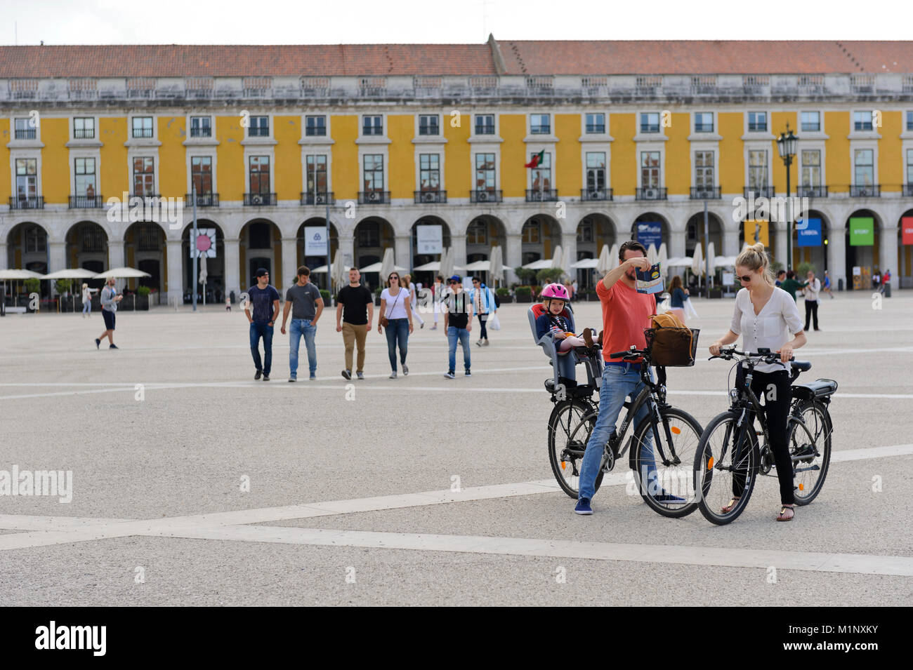 A young couple with their small child sitting on the back of the father's bicycle in the Praça do Comércio, Lisbon, Portugal Stock Photo