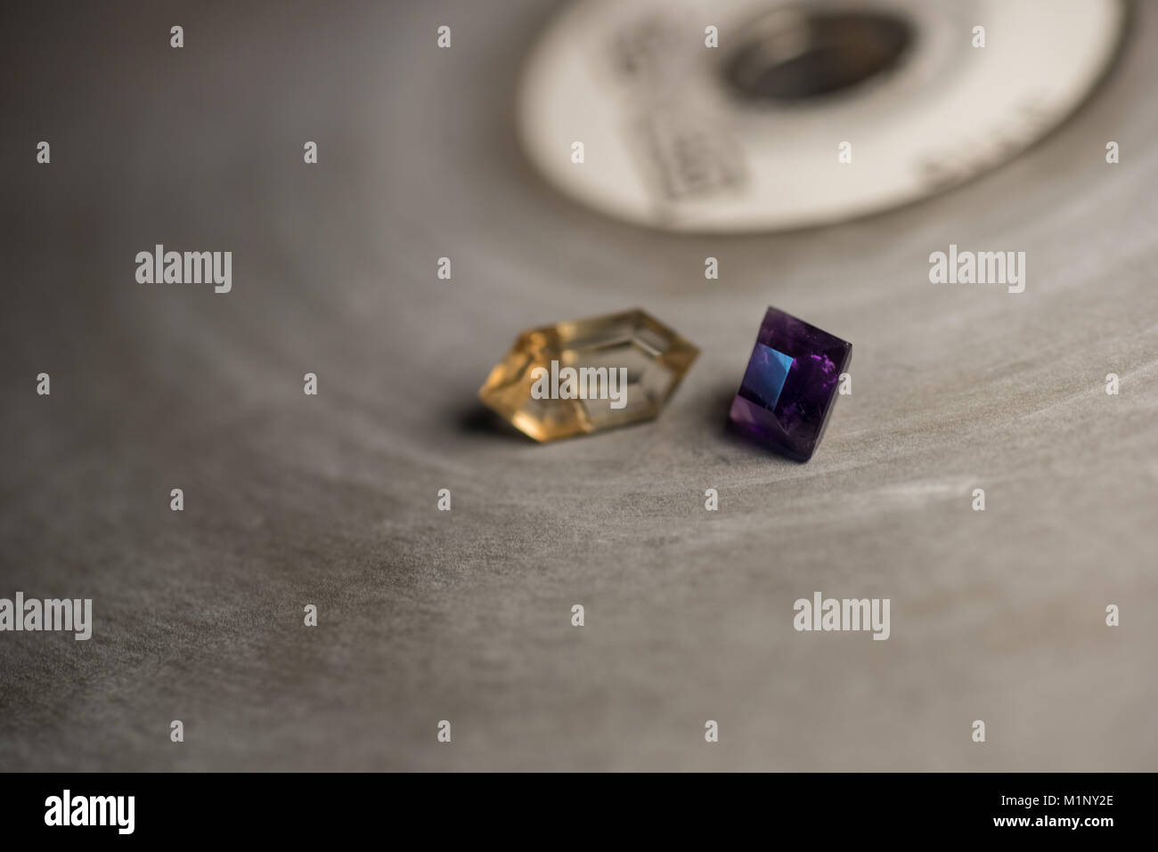 Amethyst and sunstone on a faceting lap with shallow depth-of-field. Stock Photo