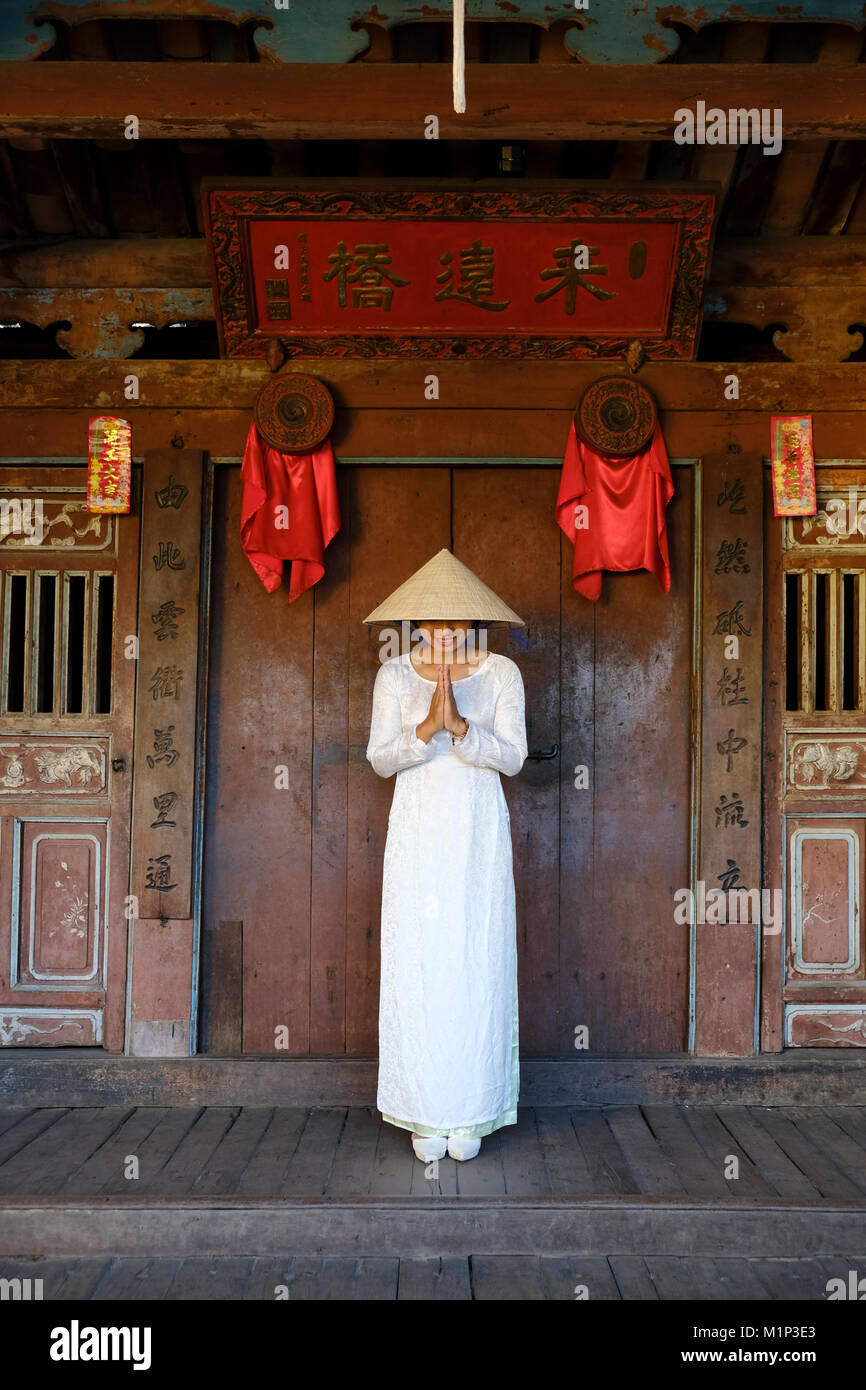 A young woman in a Non La conical hat and a traditional Ao Dai dress in the historical centre, Hoi An, Quang Nam, Vietnam, Indochina, Southeast Asia Stock Photo