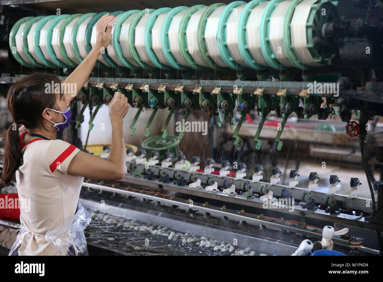 Woman working on silk spinning machine in traditional silk factory, Dalat, Vietnam, Indochina, Southeast Asia, Asia Stock Photo