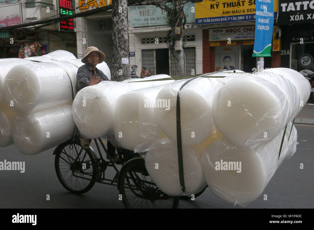 Man pedals a trishaw, loaded with rolls on a road, Ho Chi Minh City, Vietnam, Indochina, Southeast Asia, Asia Stock Photo