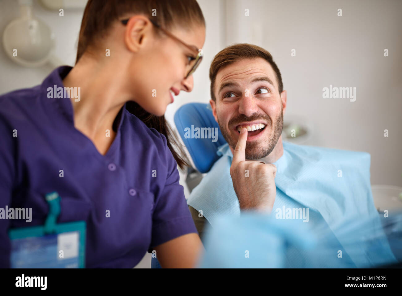 Patient shows problematic tooth to young female dentist Stock Photo