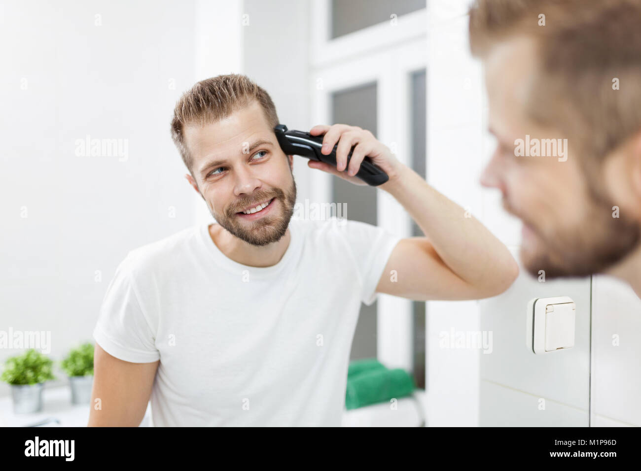 Handsome Bearded Man Cutting His Own Hair With A Clipper Stock