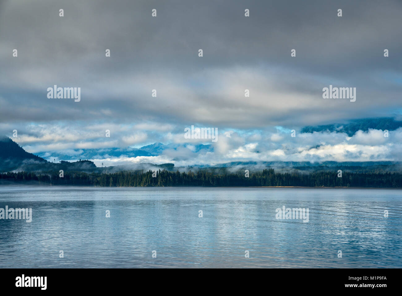 Vancouver Island shoreline, shrouded with clouds, view from ferry crossing Broughton Strait on its way to Alert Bay, British Columbia, Canada Stock Photo