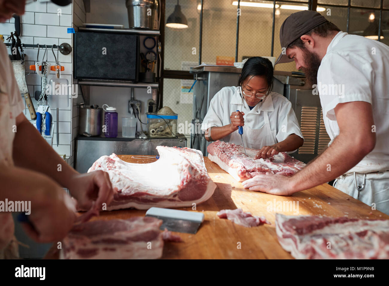 Three butchers preparing meat,cuts of meat to sell at a butcher's shop Stock Photo