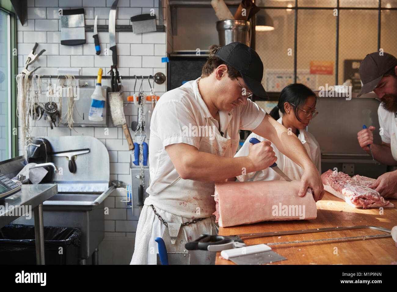 Three butchers preparing meat,cuts of meat at a butcher's shop Stock Photo