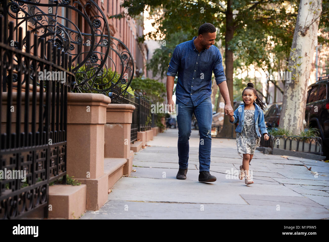 Father and daughter taking a walk down the street Stock Photo