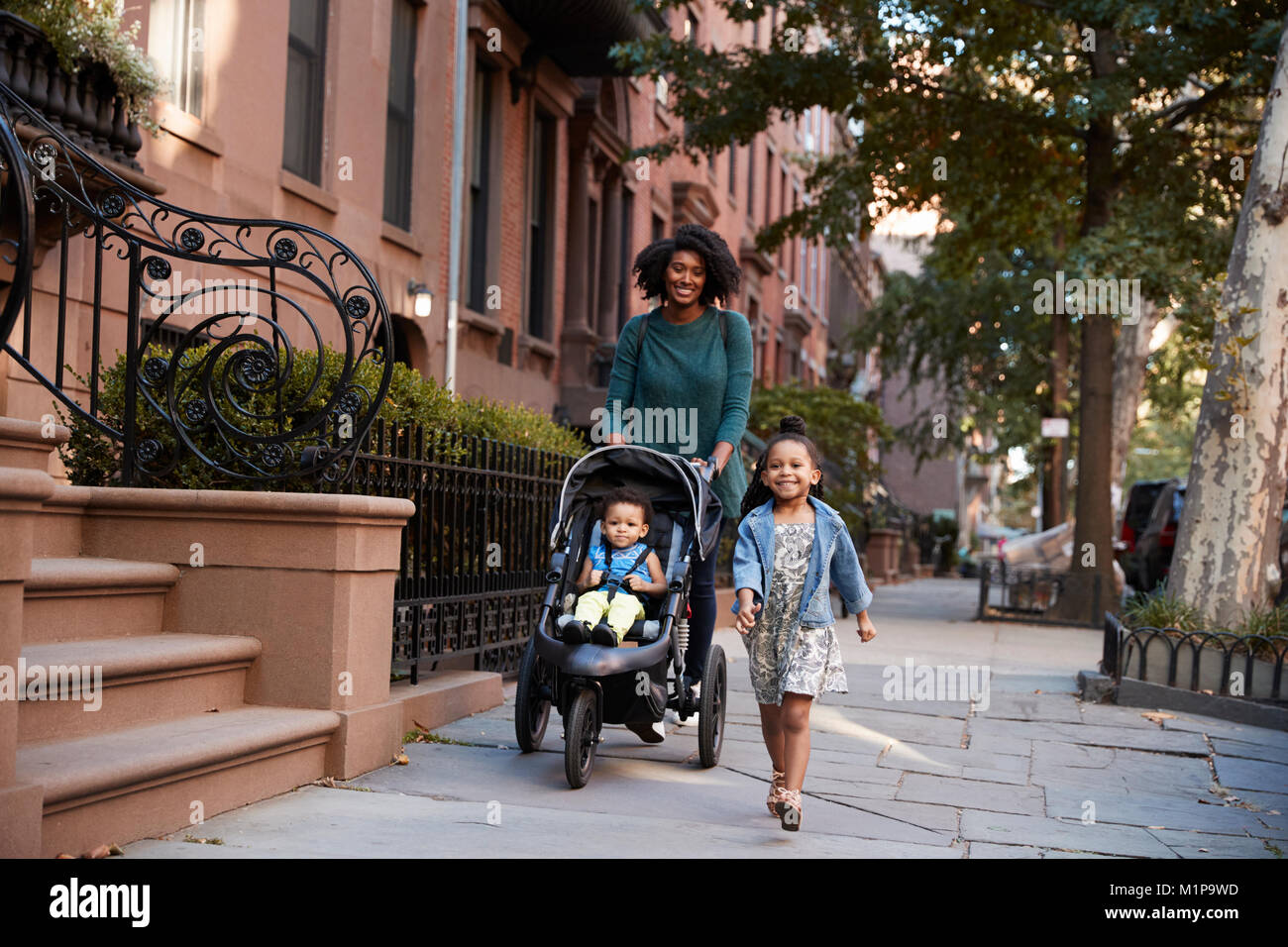 Mother and two daughters taking a walk down the street Stock Photo