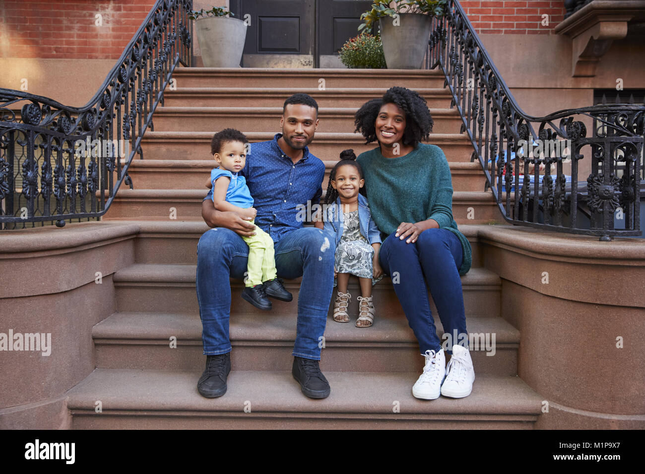 Young family with kids sitting on front stoops Stock Photo