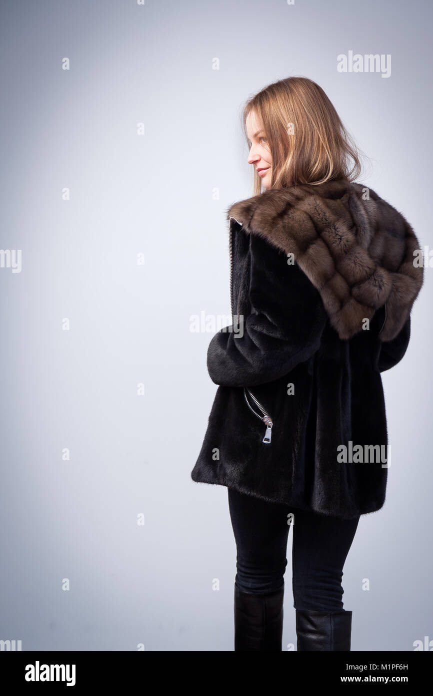 Young dark-haired woman in black fur coat from natural mink fur posing ...