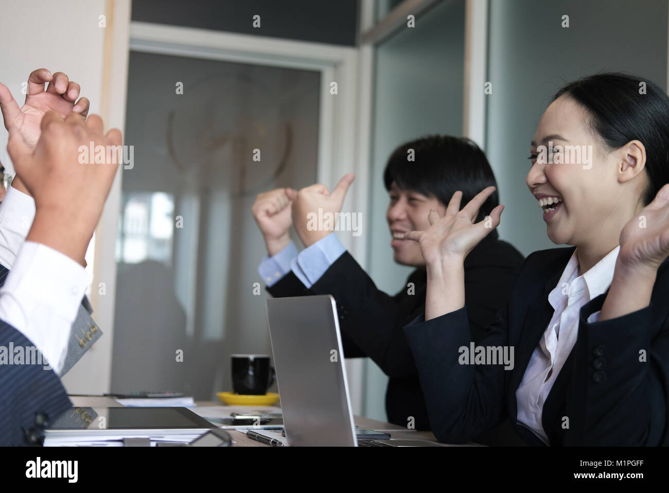 business team raise hands with happiness for successful project. cheerful asian businessman & businesswoman showing gladness for achievement Stock Photo