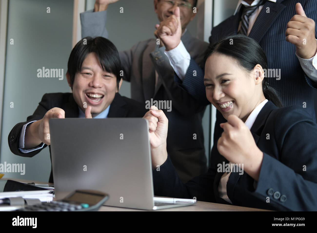 business team raise hands with happiness for successful project. cheerful asian businessman & businesswoman showing gladness for achievement Stock Photo