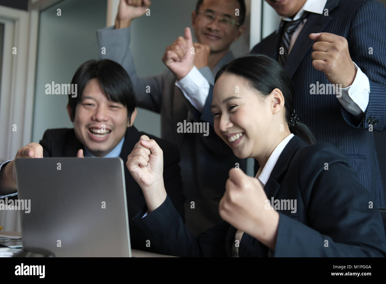business team raise hands with happiness for successful project. cheerful asian businessman & businesswoman showing gladness for achievement Stock Photo