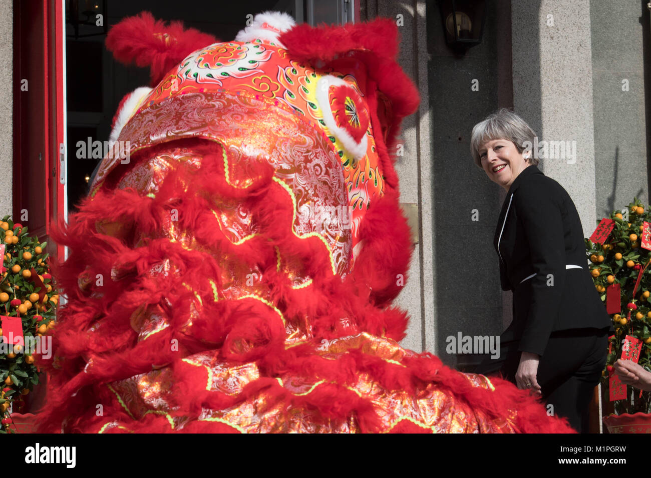 Prime Minister Theresa May 'dots the eye' of a Chinese dragon, a traditional ritual of awakening a dragon, in the grounds of the British Embassy in Beijing today on the second day of a three day trade mission to China. Stock Photo