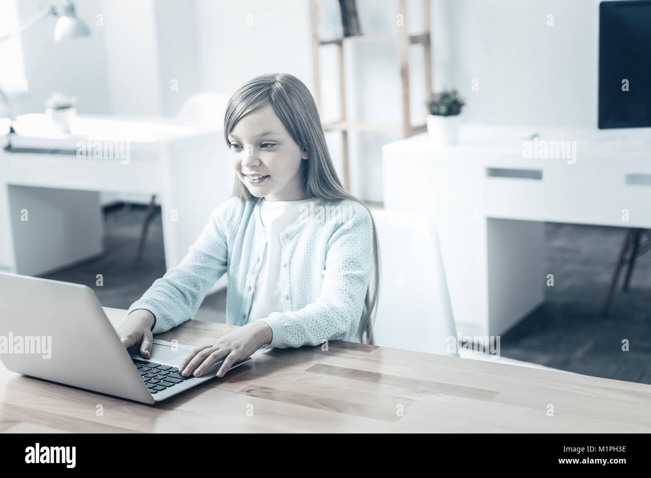 Cheerful preteen girl smiling while working on laptop Stock Photo - Alamy