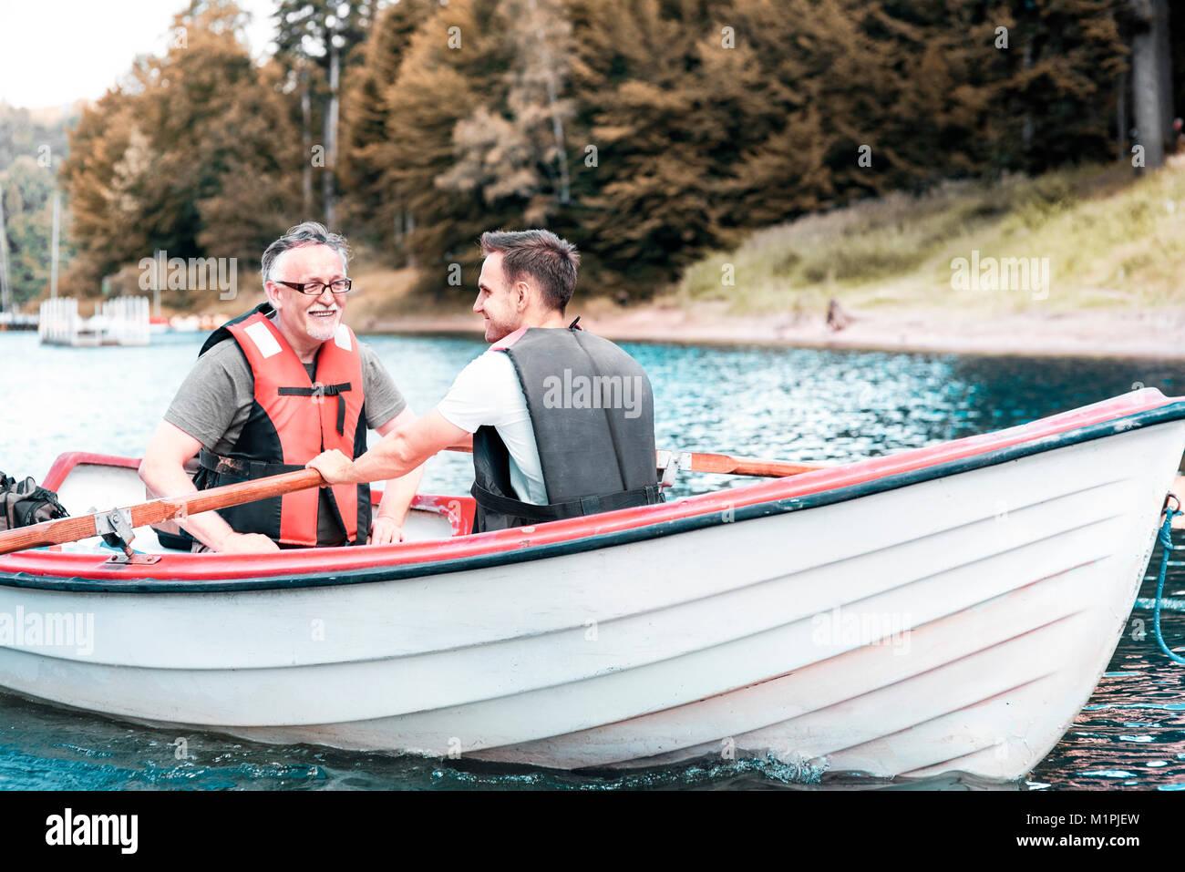 Two men rowing a boat on the tranquil lake Stock Photo